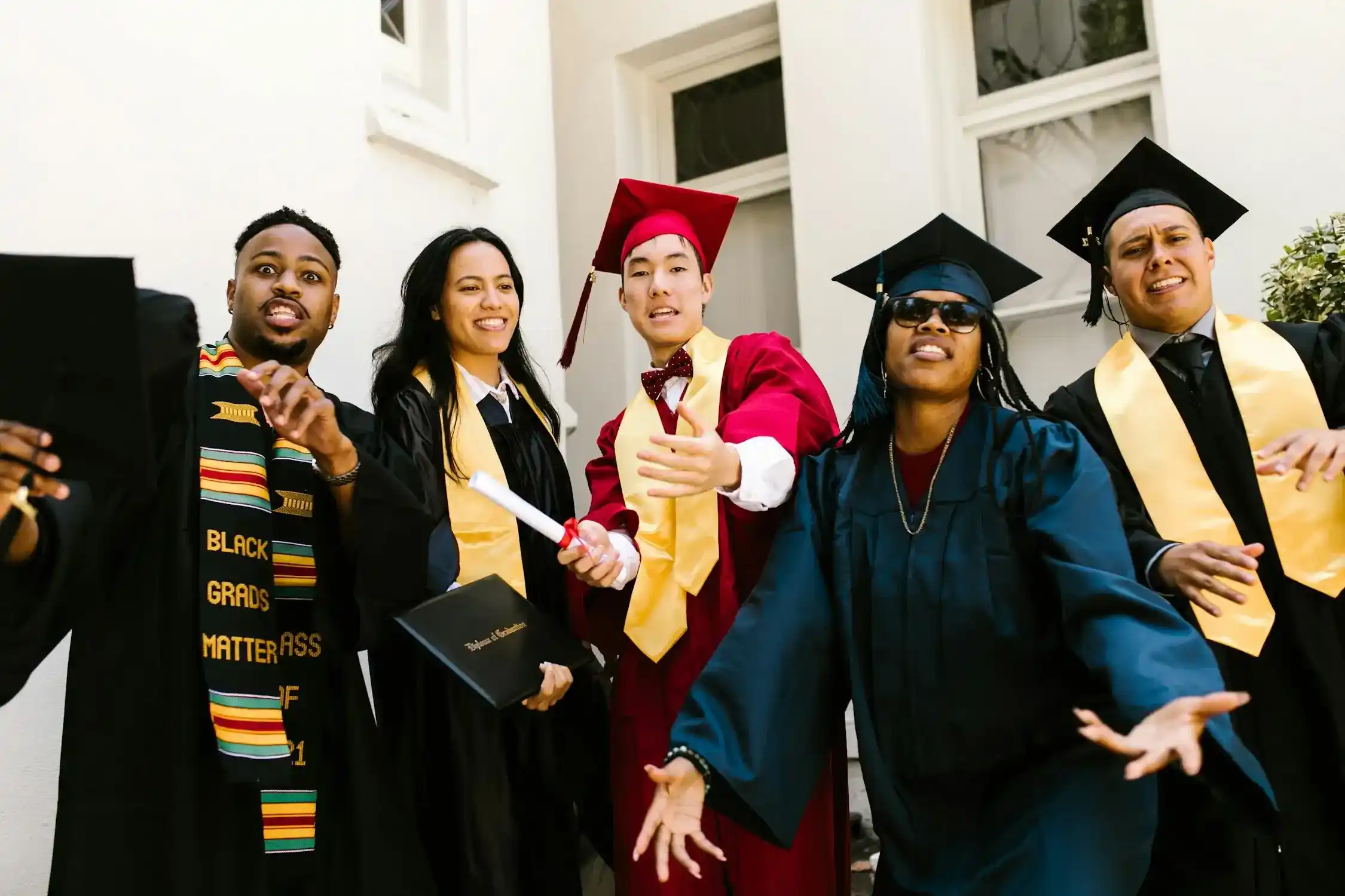 Recent graduates in caps and gowns, smiling and holding diplomas